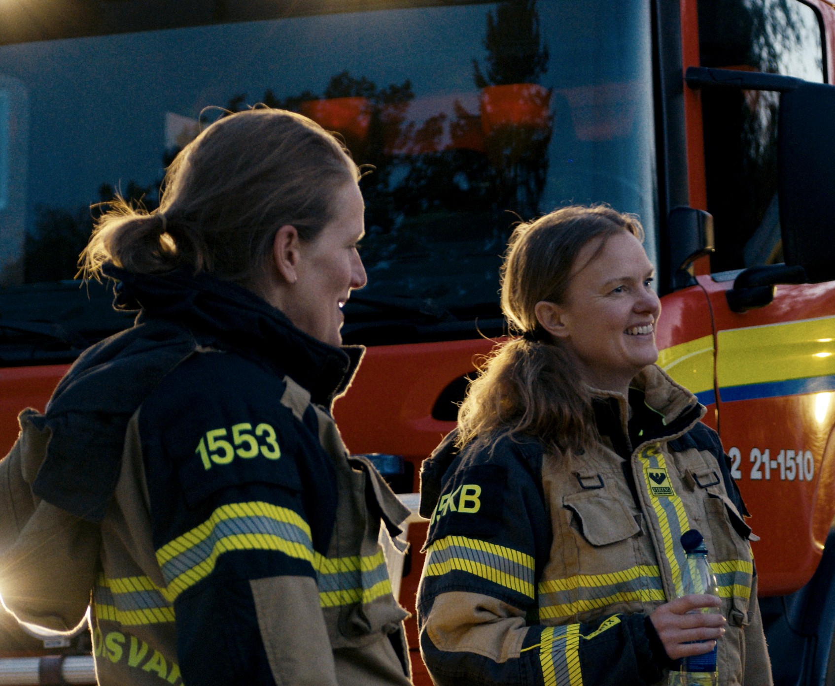 Två kvinnliga brandmän framför brandbil